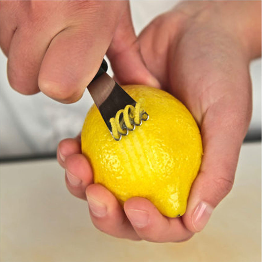 A stainless steel lemon zester in use.