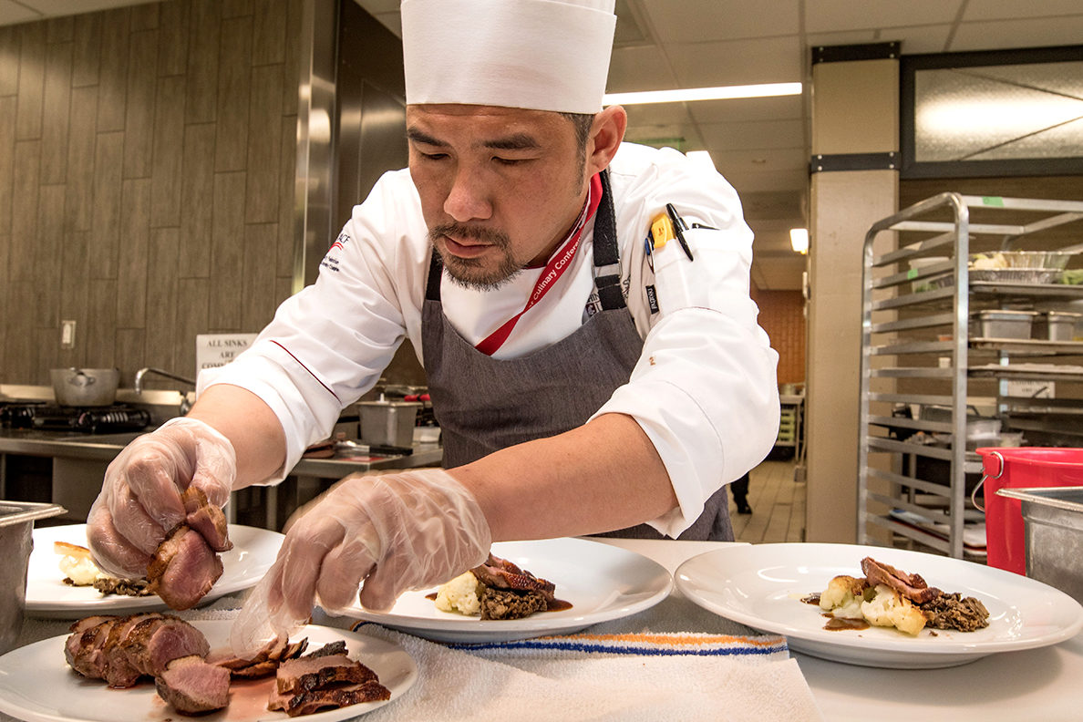 A chef in the process of plating.