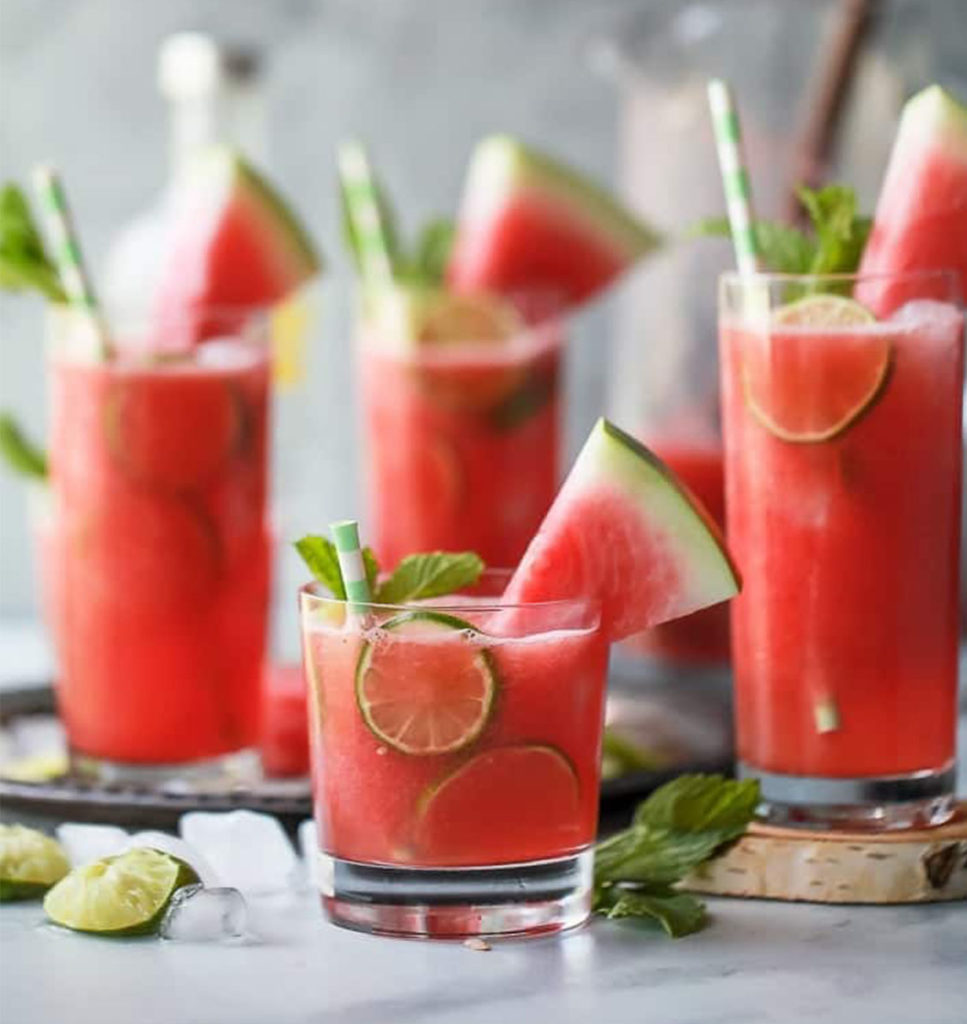 Watermelon shots with sugar rims and slices of lime.