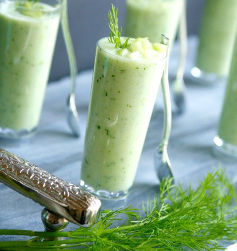 A healthy cucumber and melon smoothie shot with dill as garnish.